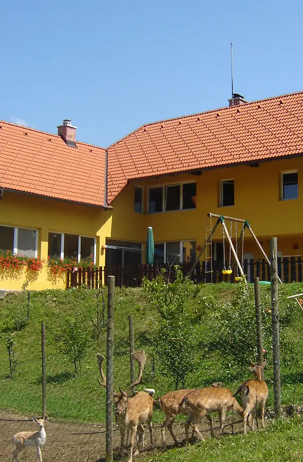 Domačija z lovilnikom Prevectron na drogu ob dimniku, spredaj jelenjad v obori