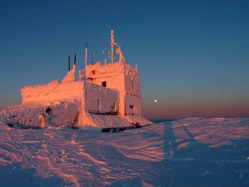 Meteorološka postaja na vrhu Omu v Romuniji pozimi, ob sončnem zahodu